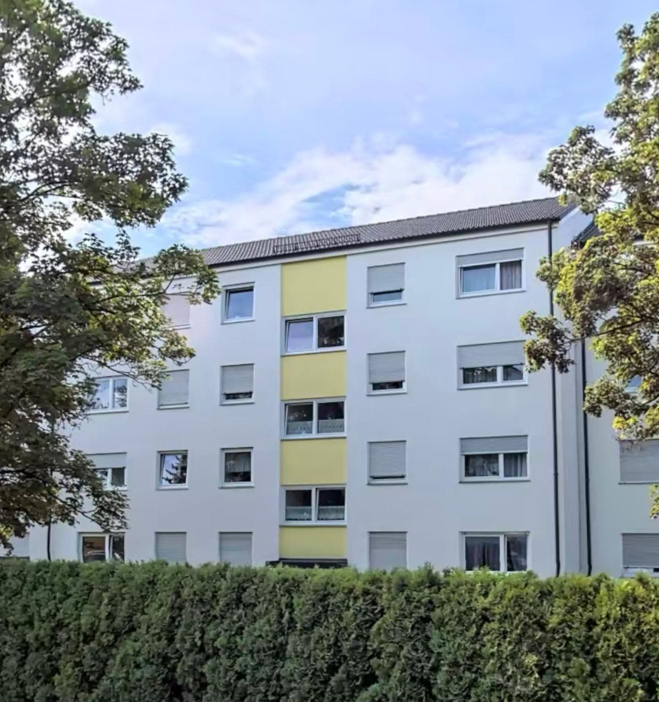 Mehrfamilienhaus mit heller Fassade im Sommer